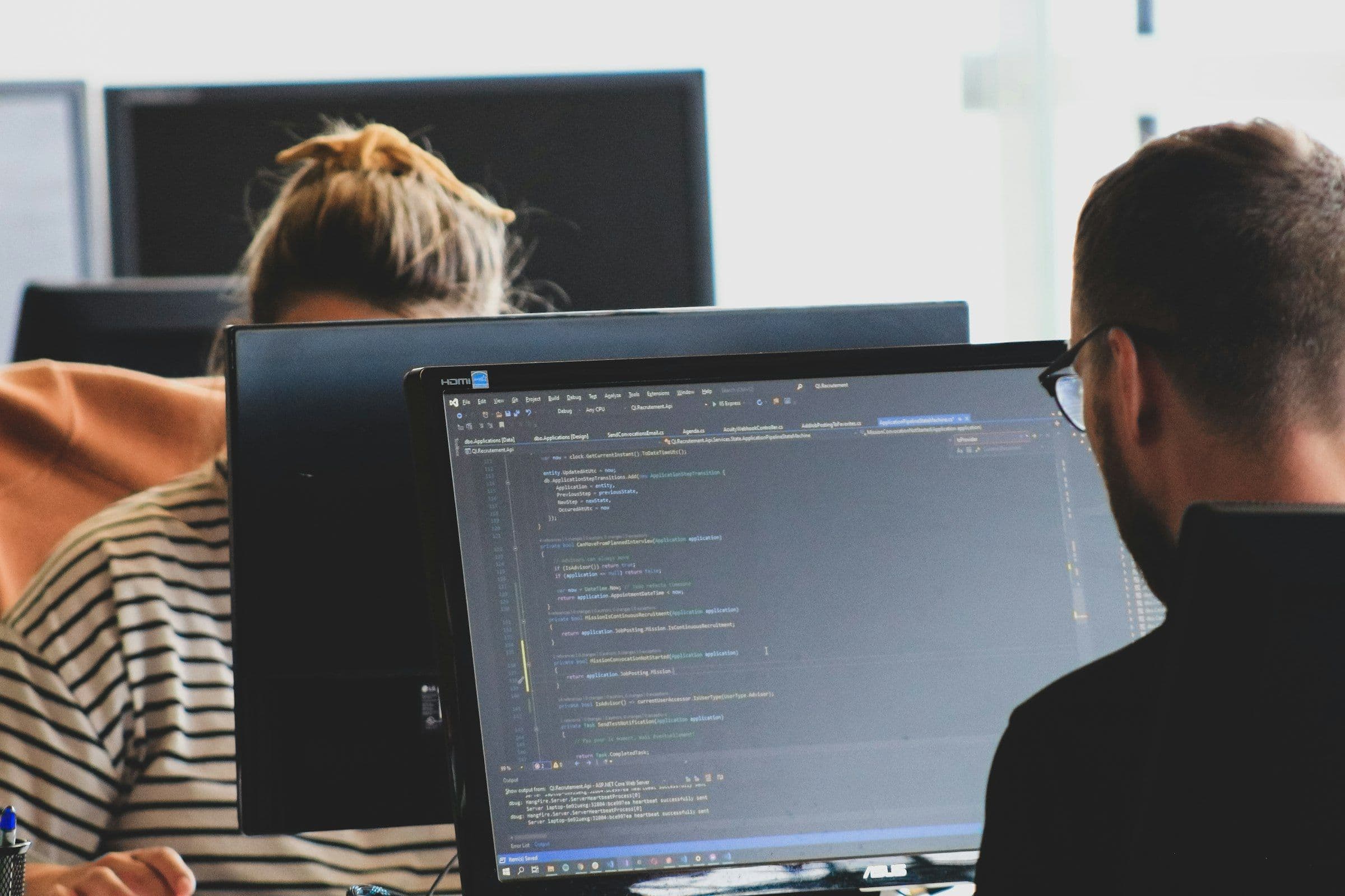 Two developers working through code at their monitors during a website rebuild